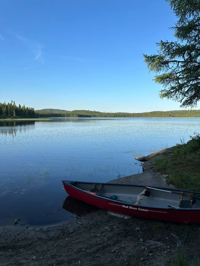 The red Mad River canoe pulled up on a sandy shore of a glassy blue lake at camp.
