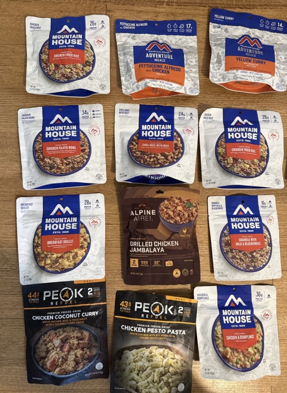 Assorted freeze-dried dinners: Mountain House Chicken Fried Rice, Fettuccine Alfredo, Yellow Curry, Chicken Fajita Bowl, Chili Mac, and others.